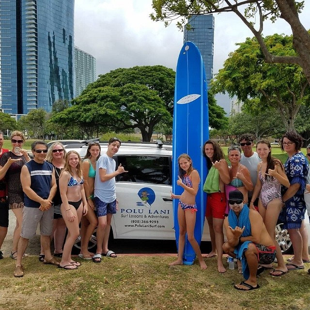 Photo of a large group in front of the Polu Lani Surf van, heading out to catch some waves. Shakas all around. Provided by Polu Lani Surf 