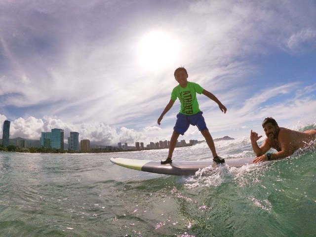 A young boy and instructor, John, catching a wave together. Provided by Polu Lani Surf.