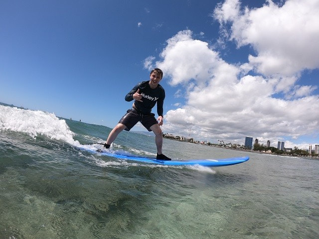 A young boy, riding a wave throwing a shaka. Provided by Polu Lani Surf.