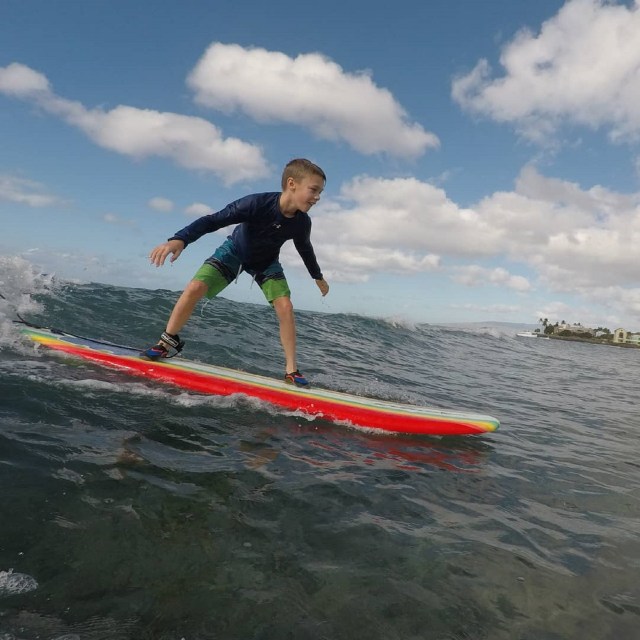 A young boy riding a wave. Provided by Polu Lani Surf.