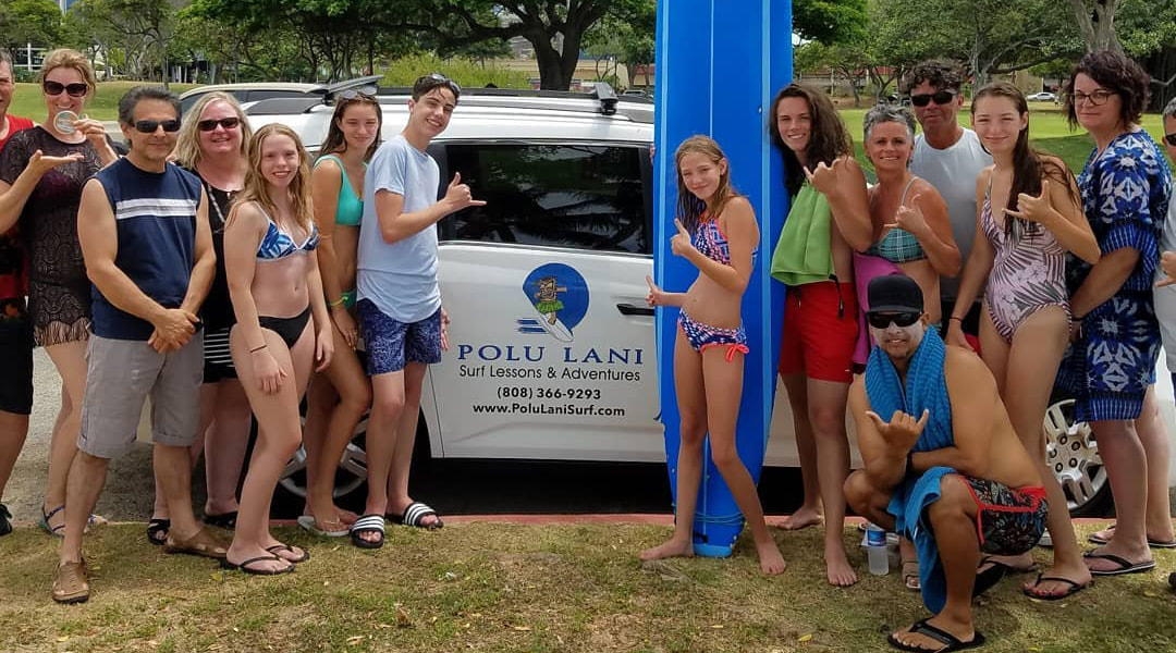 Photo of a large group in front of the Polu Lani Surf van, heading out to catch some waves. Shakas all around. Provided by Polu Lani Surf 