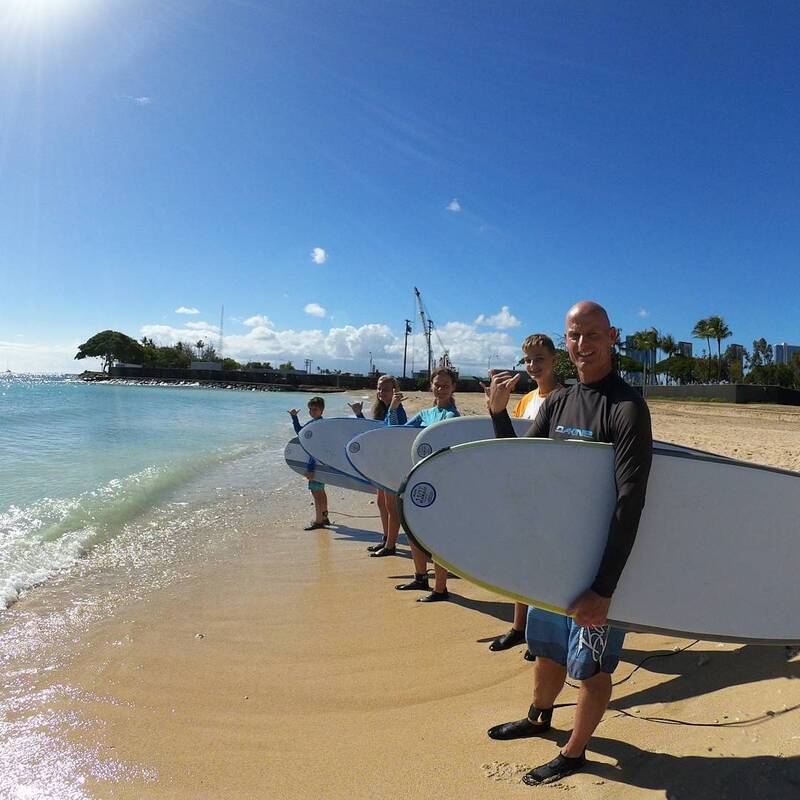 Family of 5 on the beach throwing some shakas, heading out to catch some waves. Provided by Polu Lani Surf
