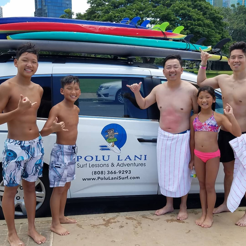 A family of 5 throwing shakas in front of the Polu Lani Surf van, after their private surf lesson. Provided by Polu Lani Surf.